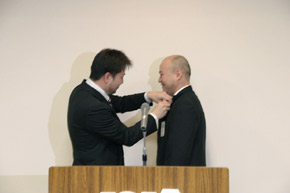 理事長よりバッジ授与された長谷川君